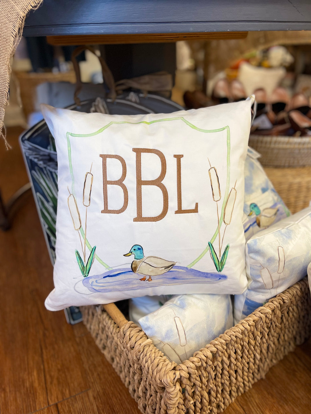 Decorative pillow with 'BBL' and duck illustration in a basket