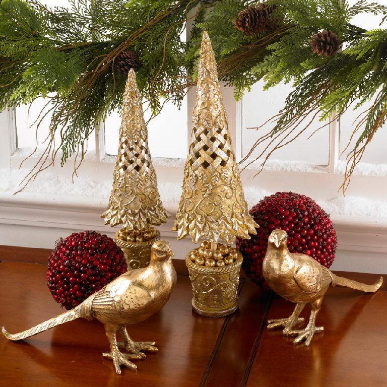 Decorative Christmas scene with gold trees, birds, and red berries on a wooden surface.