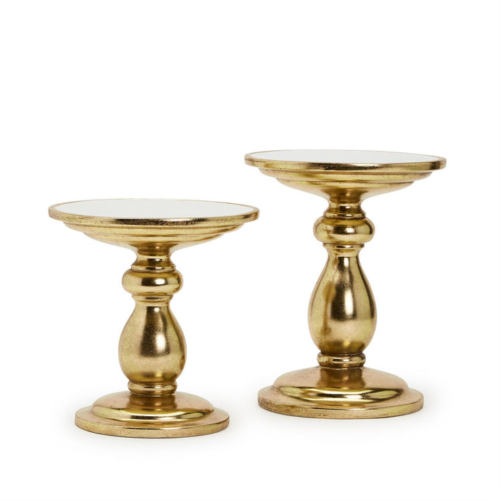 Two gold candle holders with white tops on a white background