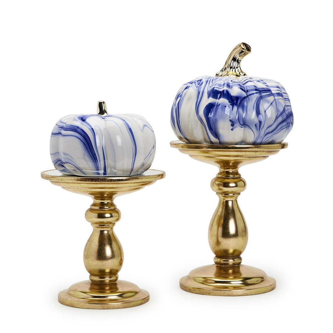 Two blue and white marbled pumpkins on gold stands against a white background