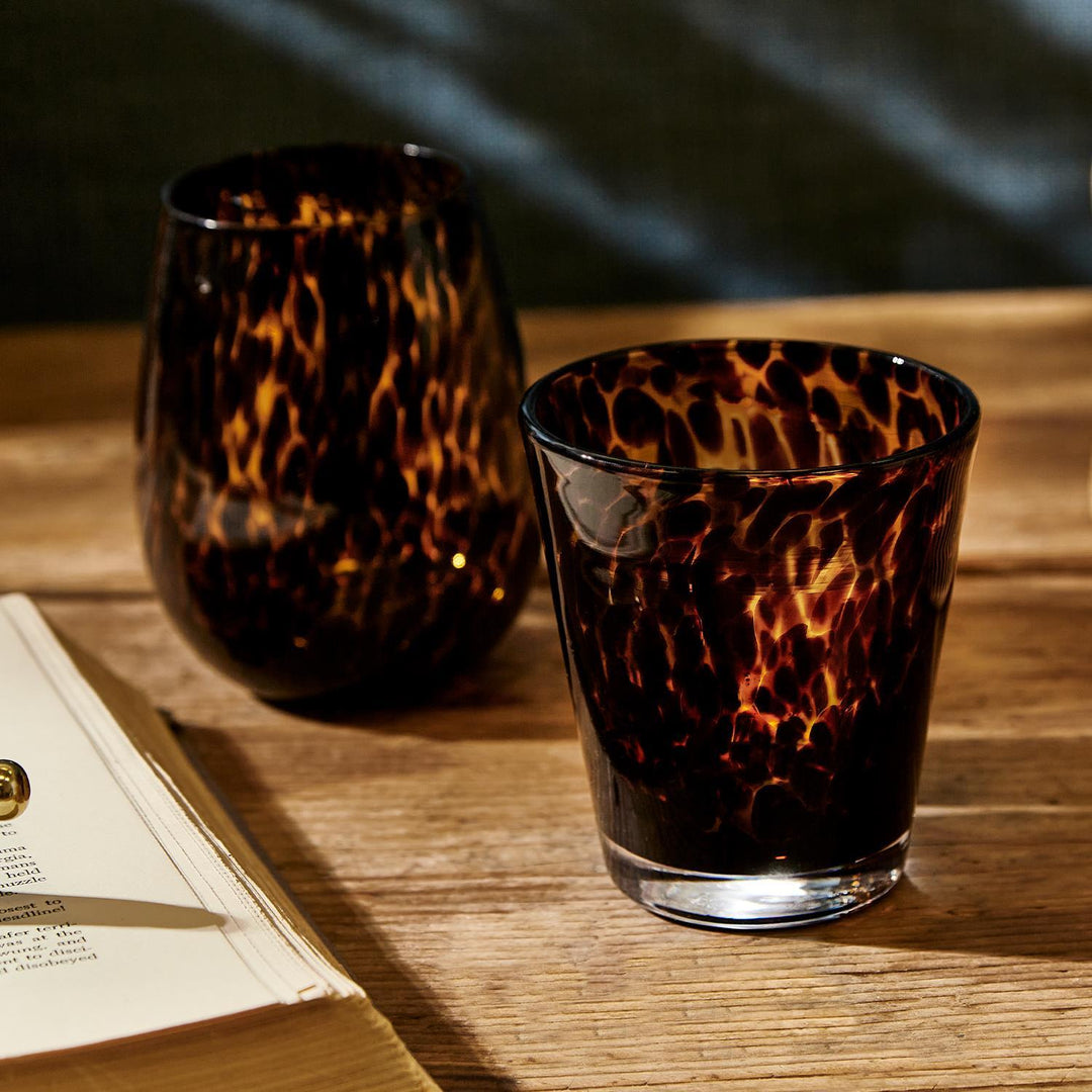 Two tortoiseshell-patterned glasses on a wooden surface with an open book.