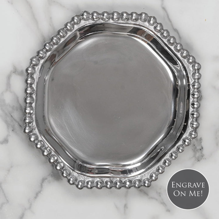 Silver decorative plate with beaded edge on a marble background