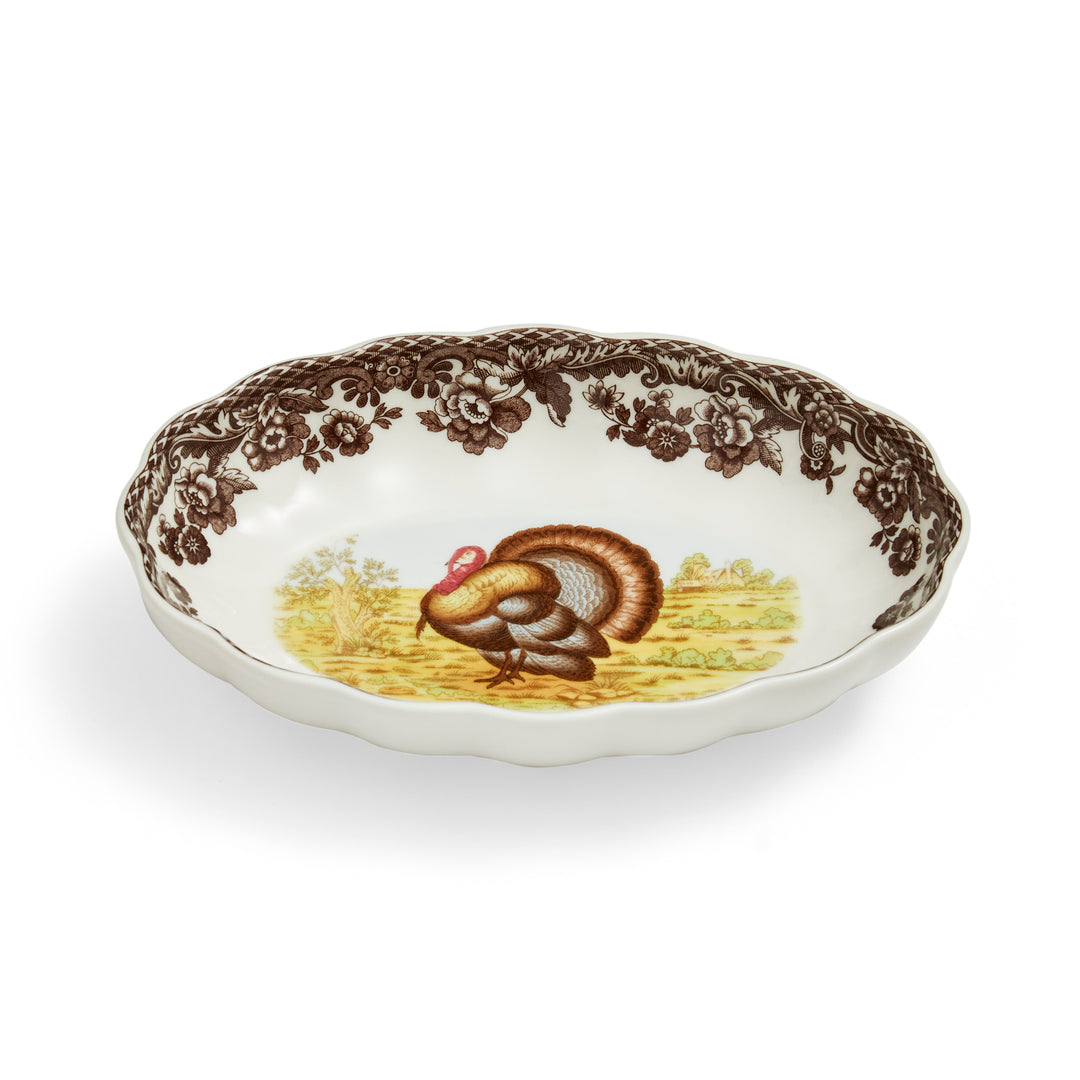 An oval fluted dish with a turkey design in the center, surrounded by a brown patterned border on a white background.