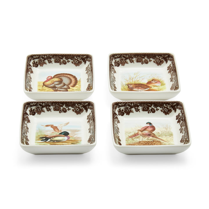 A set of four square porcelain dishes with assorted animal motifs and brown decorative patterns around the edges.