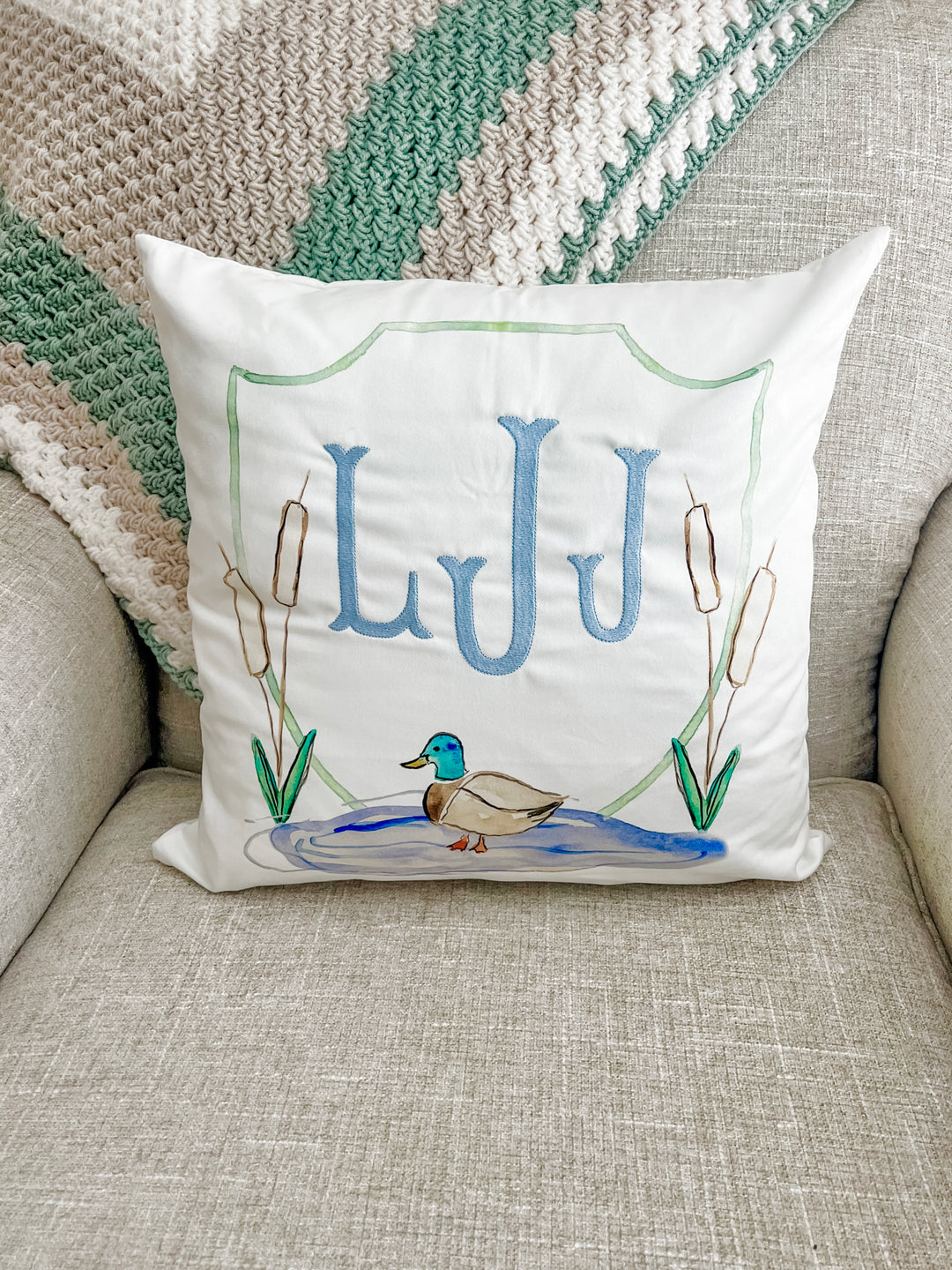 Decorative pillow with 'LUU' initials and a duck illustration on a couch.