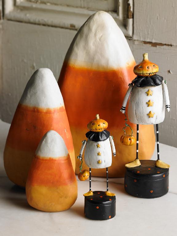Halloween-themed candy corn and pumpkin decorations on a neutral background