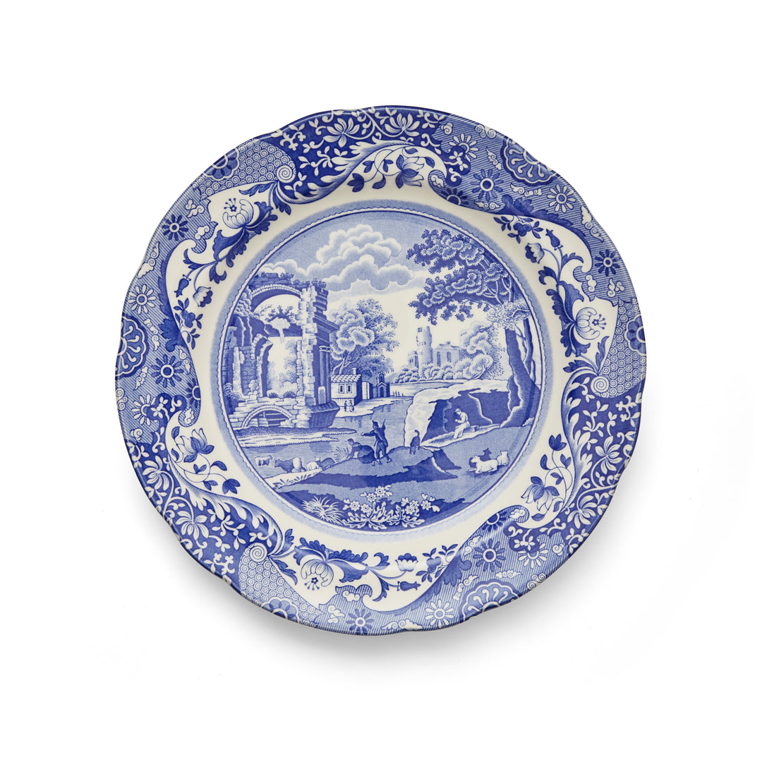A blue and white floral patterned dinner plate with a central landscape design