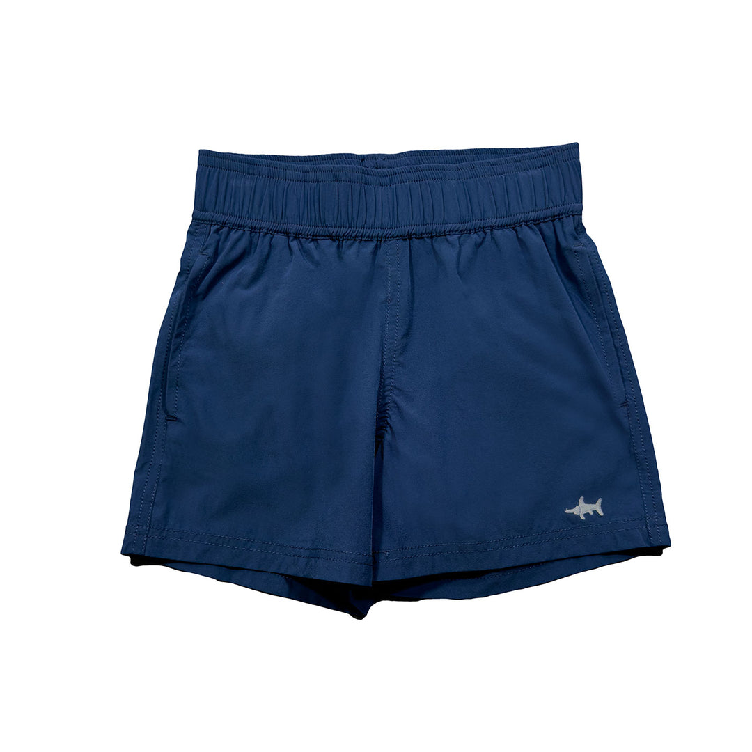A pair of navy blue performance shorts for boys, with a shark logo on the left leg.