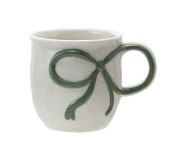 White mug with a green bow design on a white background