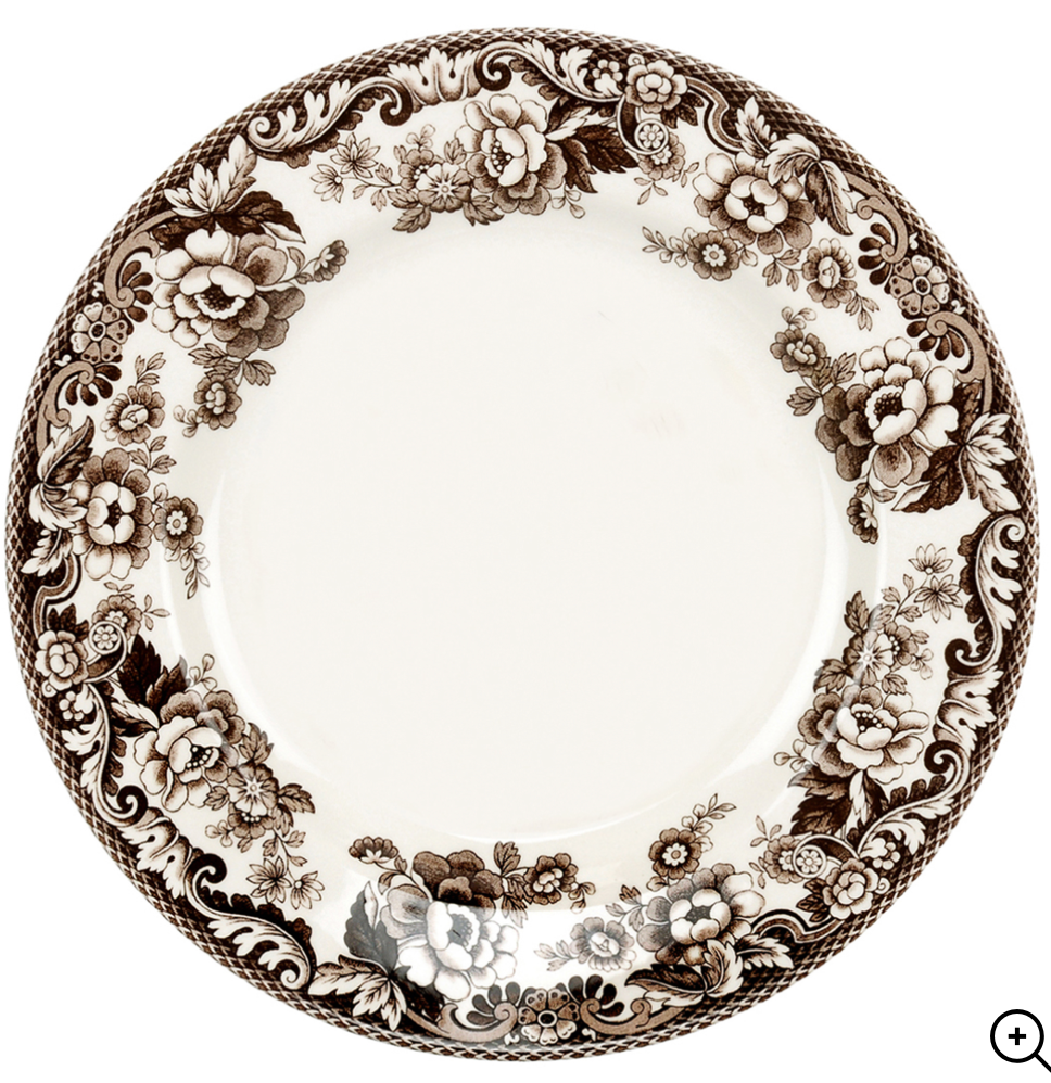 A fine porcelain dinner plate with a floral pattern in brown shades around the rim, with a central motif of a floral design.