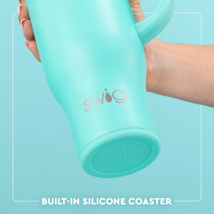 Turquoise tumbler with built-in silicone coaster held by a hand against a light blue background