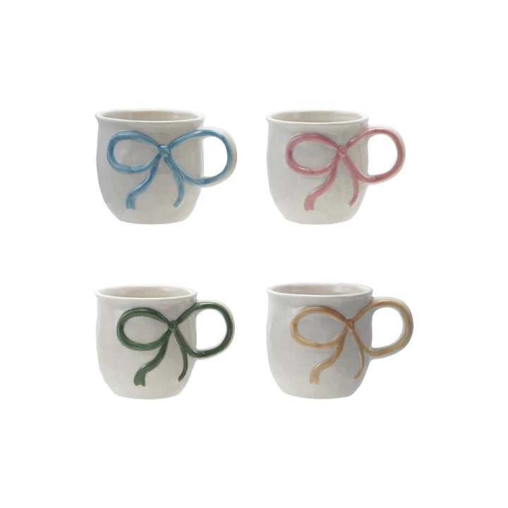 Four ceramic mugs with decorative bows on a white background