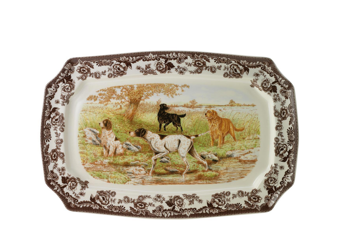 A rectangular ceramic platter with a floral pattern around the edge and an illustration of dogs in a outdoor setting in the center.