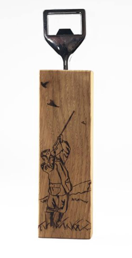 A wooden bottle opener with an engraving of a hunter shooting. The opener has a metallic finish and is attached to the wood with visible screws.