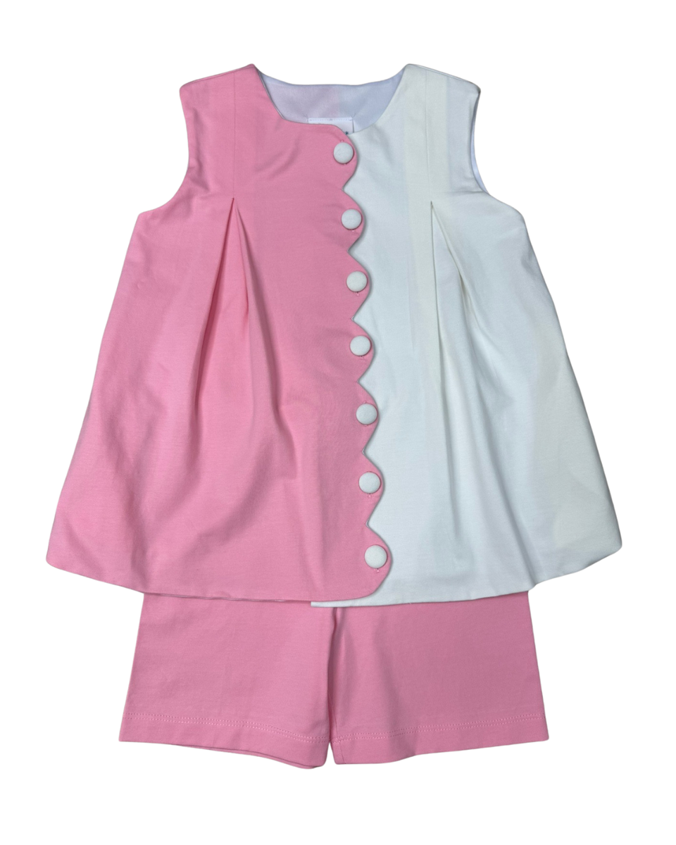 Pink and white children's outfit with button details on a white background