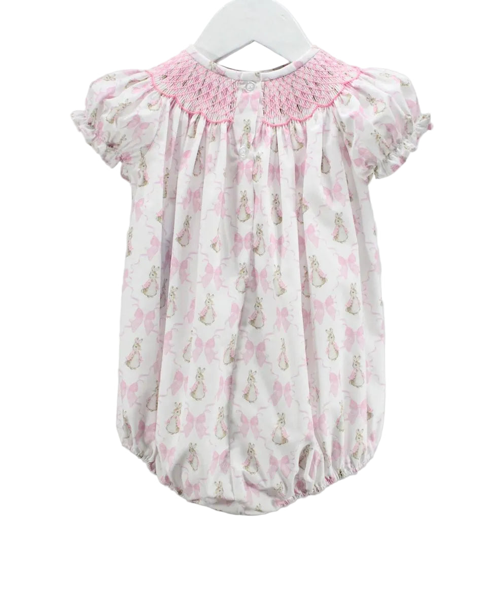 LITTLE GIRLS BUBBLE WITH PINK SMOCKED NECKLINE AND BUNNY AND BOW MOTIFS ON WHITE BACKGROUND