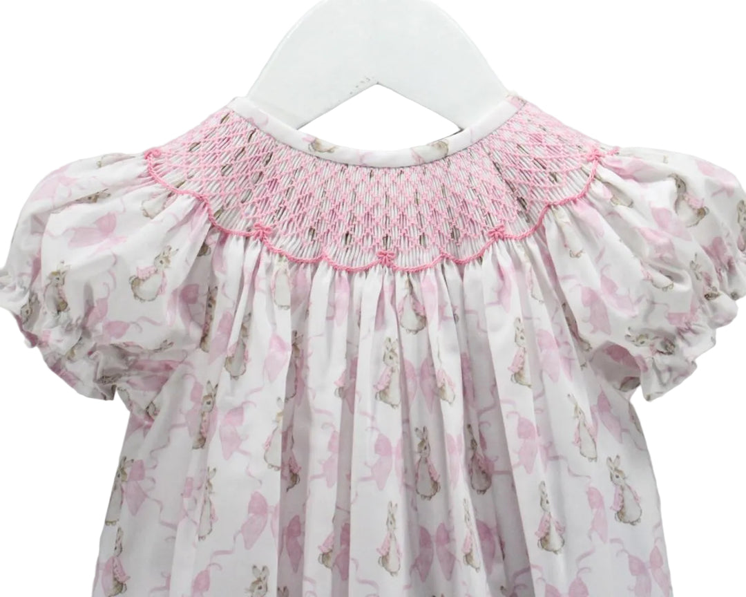 LITTLE GIRLS BUBBLE WITH PINK SMOCKED NECKLINE AND BUNNY AND BOW MOTIFS ON WHITE BACKGROUND