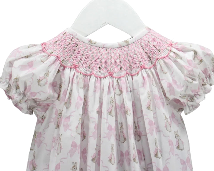 LITTLE GIRLS BUBBLE WITH PINK SMOCKED NECKLINE AND BUNNY AND BOW MOTIFS ON WHITE BACKGROUND