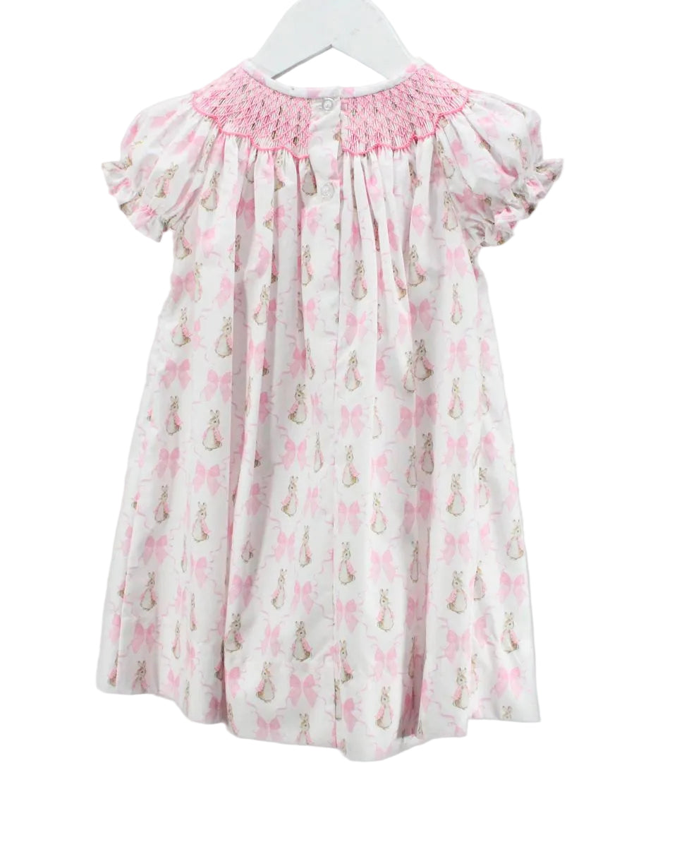 Children's dress with pink smocked neckline and bunny print on a white background