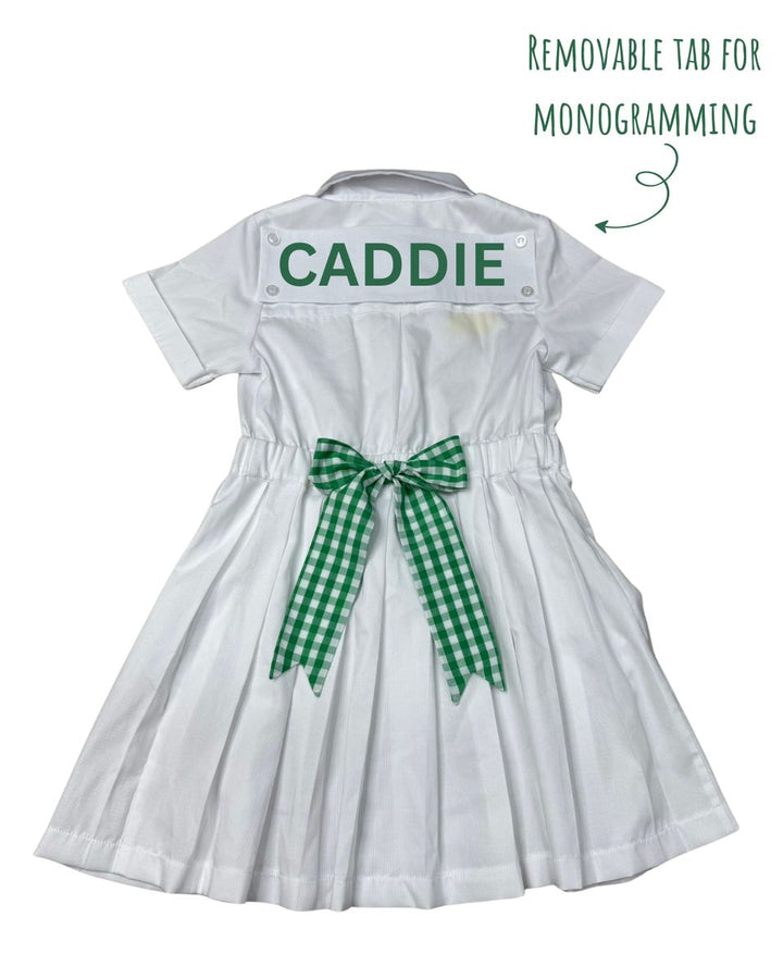 White dress with 'CADDIE' on a removable tab for monogramming, green checkered ribbon, and text indicating the feature.