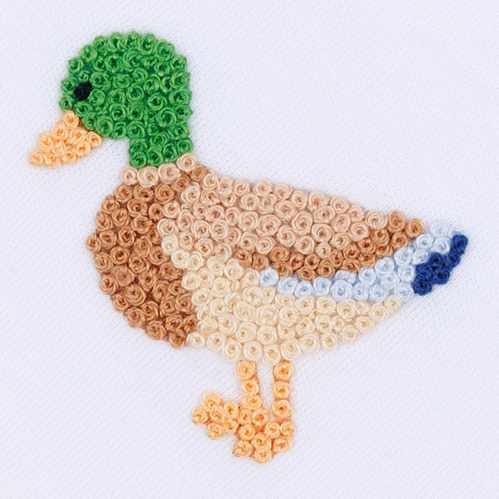 A stylized embroidered duck made from rolled fabric or thread, shown on a plain white background. The duck has a green head, peach beak and legs, tan and cream body, and a blue tail accent.
