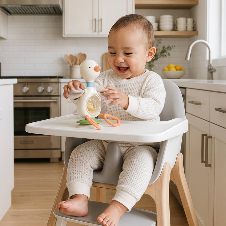 Child in a high chair playing with toys in a kitchen