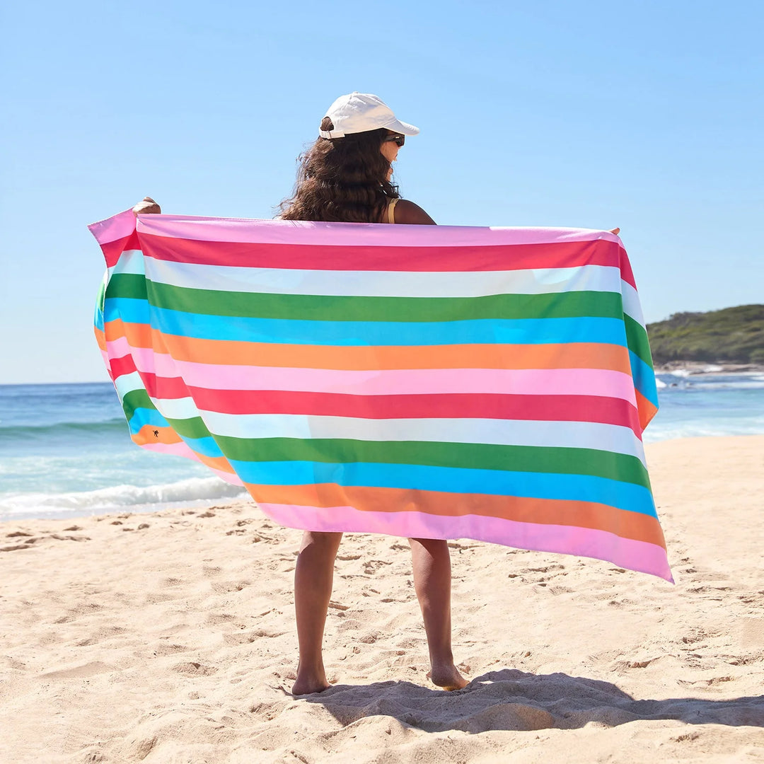 Person holding a colorful striped towel on a beach