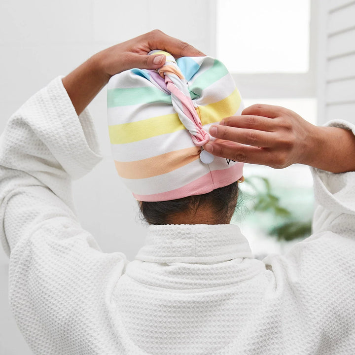 Person wearing a colorful striped towel on their head, wrapped in a white robe.