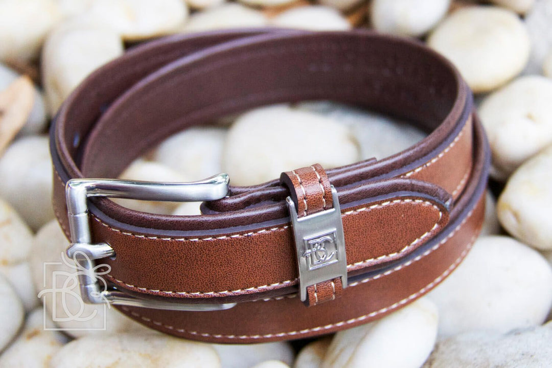 Brown leather boys belt with silver buckle on pebbles