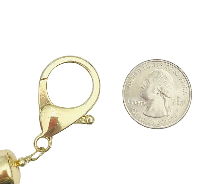 Gold lobster clasp next to a quarter on a white background
