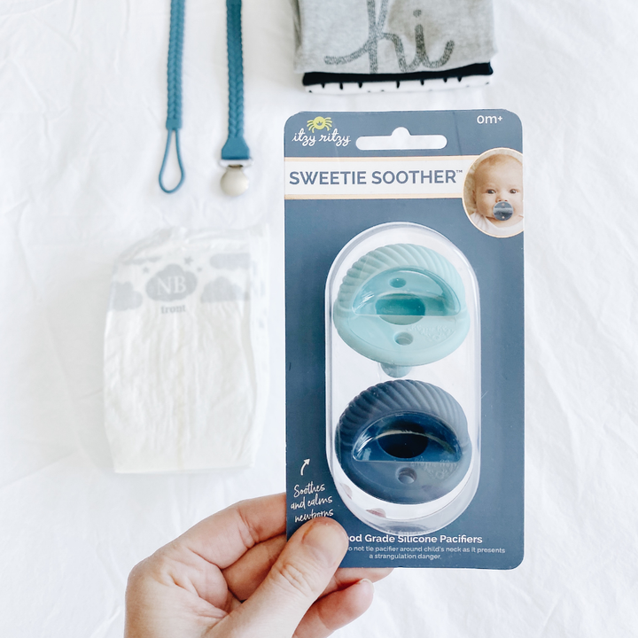 Package of Sweetie Soother silicone pacifiers held by a hand on a white background