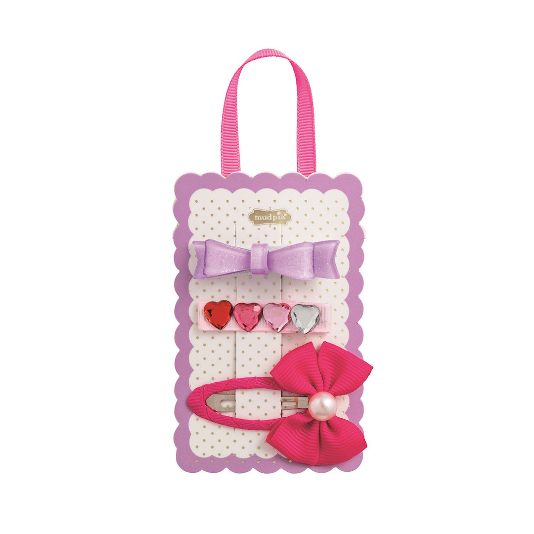 Set of hair accessories with bows and heart-shaped clips on a white background