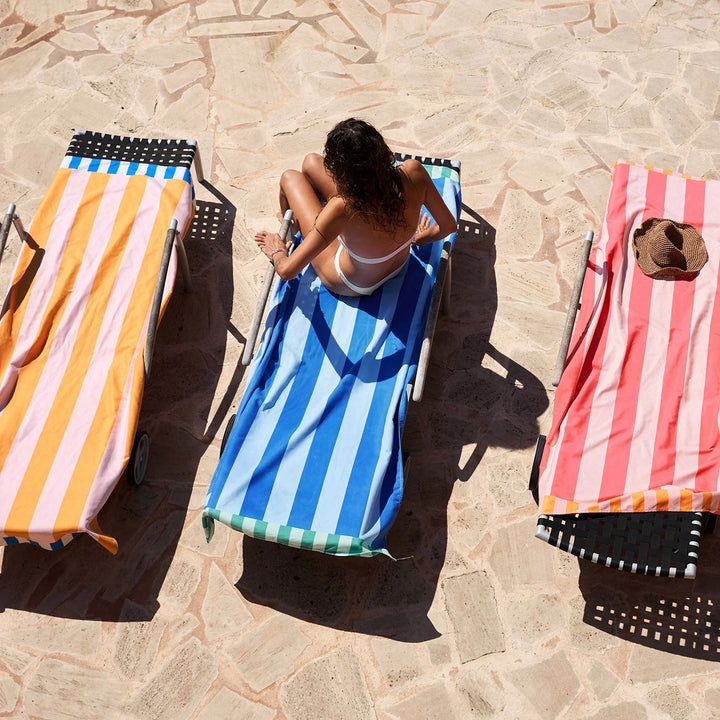 Woman sunbathing on a striped towel on a stone patio