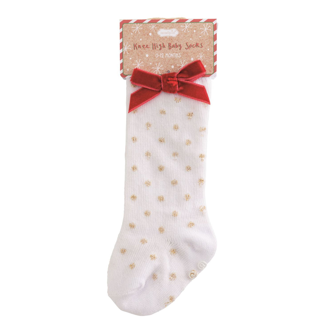 White baby sock with gold polka dots and a red bow on a white background