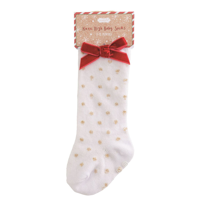 White baby sock with gold polka dots and a red bow on a white background
