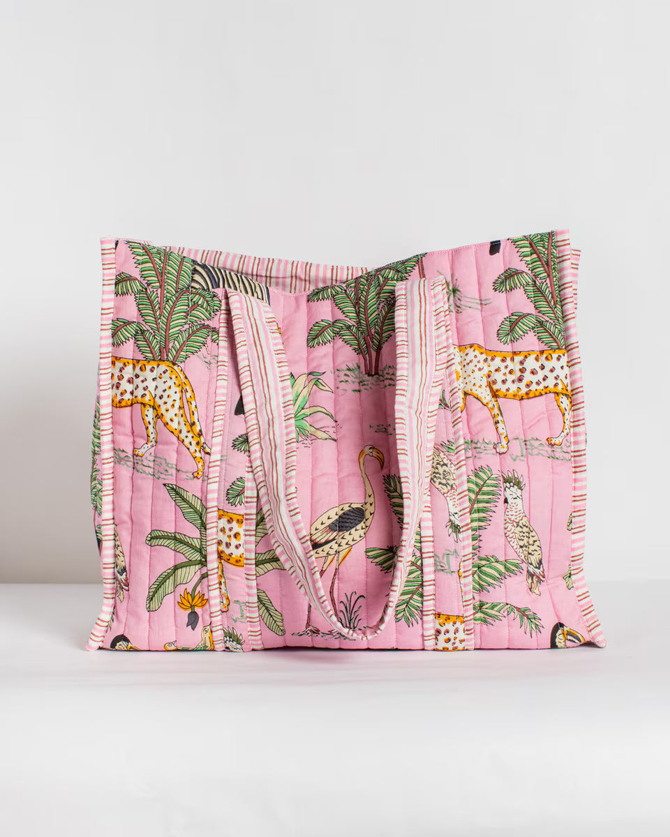 Pink quilt with animal and leaf pattern on a white background