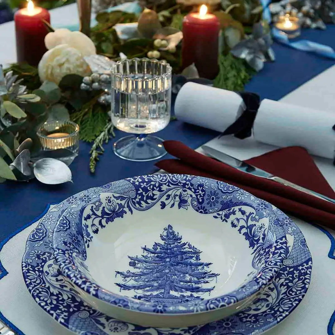Decorative blue and white plate with a pine tree design on a festive table setting.