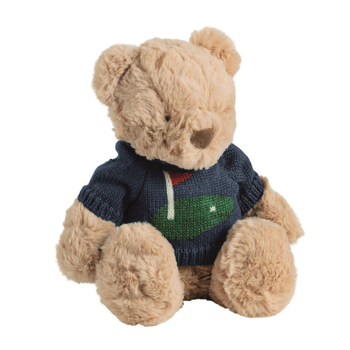 A plush teddy bear with light tan fur wearing a navy blue knit sweater with a green and white golf ball design on the chest, set against a plain white background.