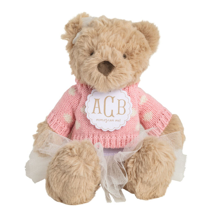 PLUSH TEDDY BEAR WEARING PINK SWEATER WITH MONOGRAM IN CENTER ON WHITE BACKGROUND