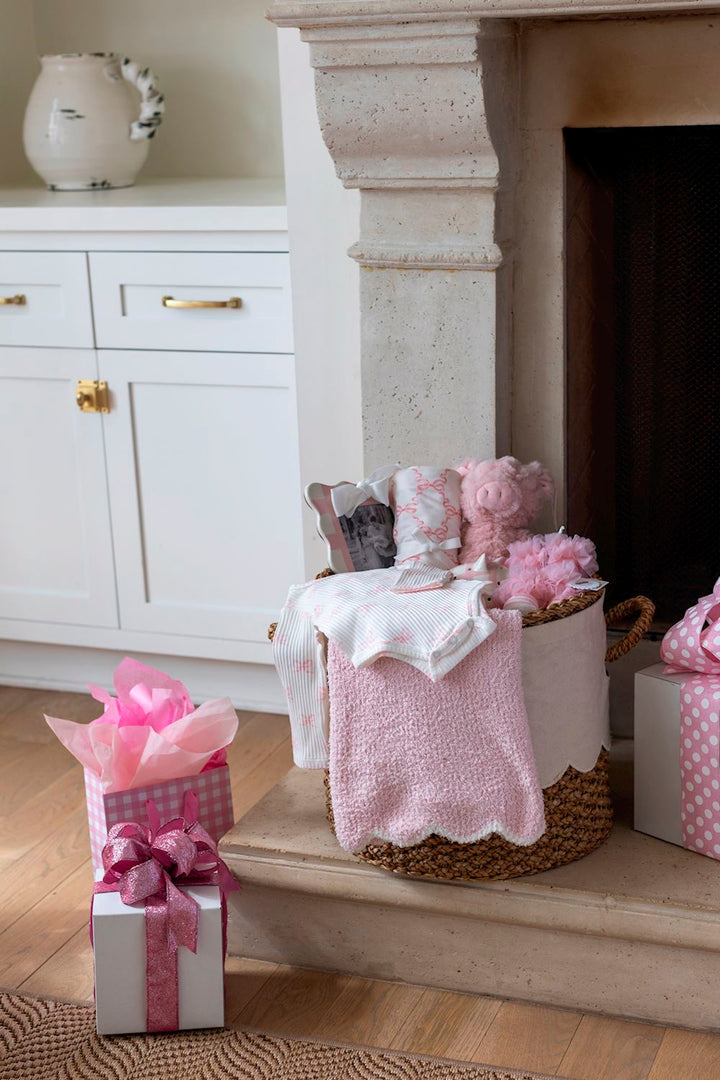 Decorative scene with pink gifts and a basket on a fireplace hearth.