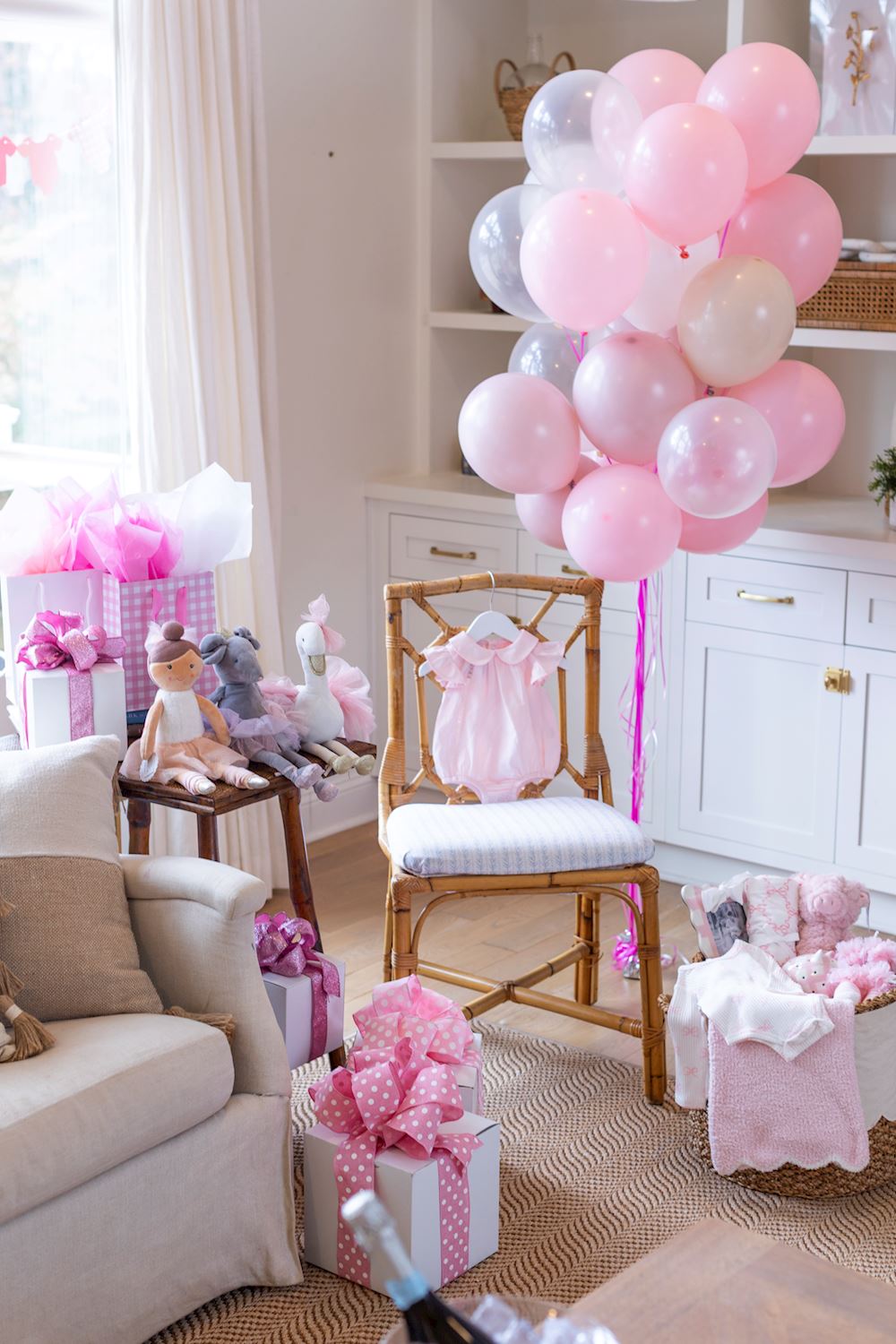 Pink and white balloons in a living room with decorative items and furniture.