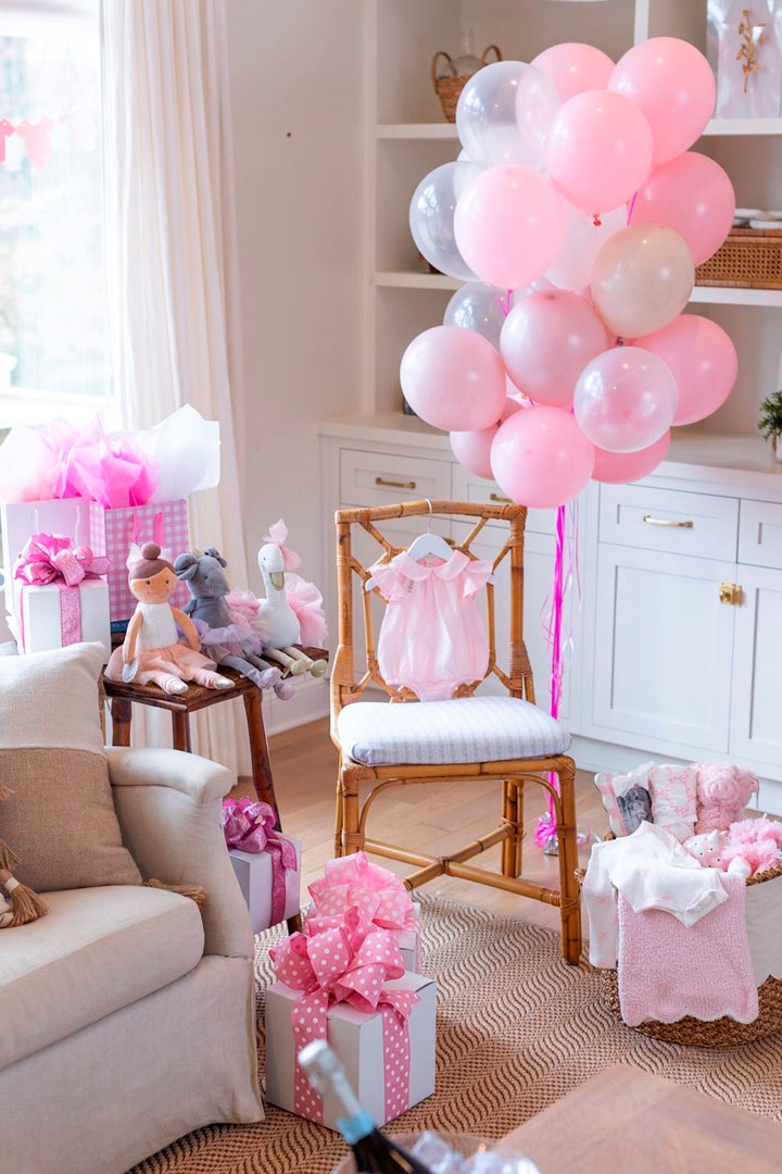 Pink and white balloons in a living room with decorative items and furniture.
