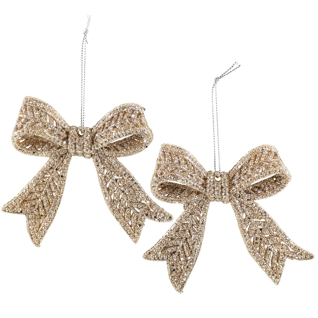 Two glittery gold bow ornaments on a white background