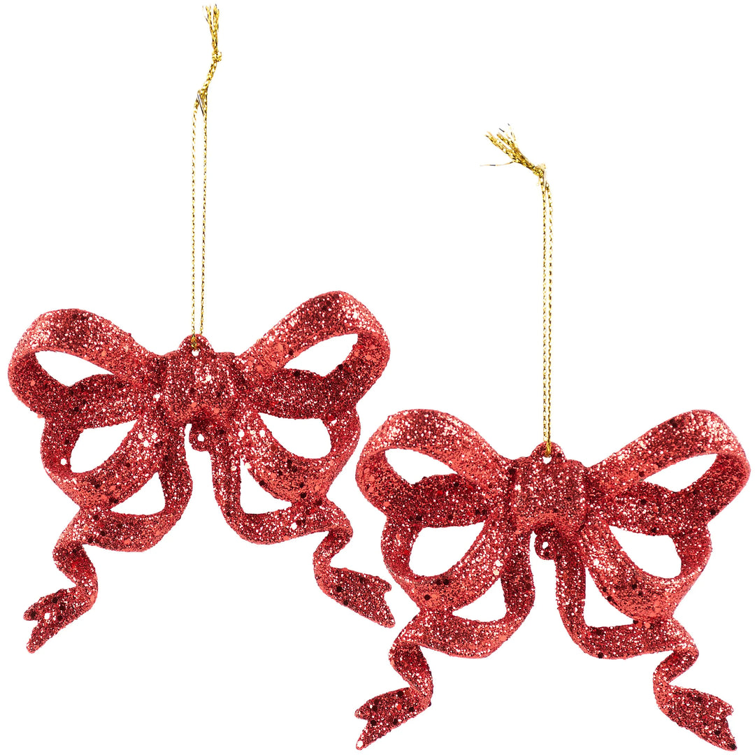 Two red glittery bow ornaments on a white background