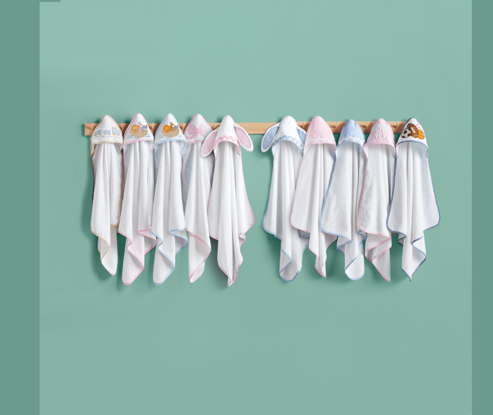 BUNNY HOODED TOWELS HANGING UP ON GREEN BACKGROUND