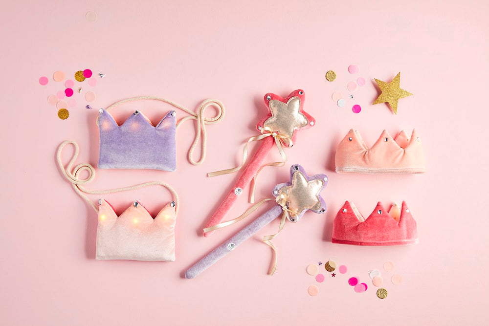 PINK AND PURPLE STAR MAGIC WAND TOY AND TOY CROWNS ON PINK BACKGROUND