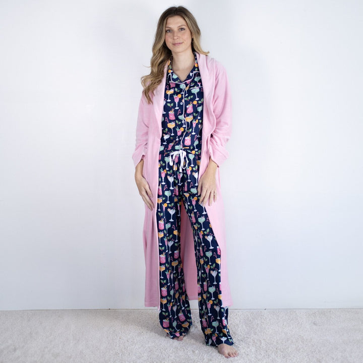 Woman wearing a pink robe over a patterned outfit on a plain background