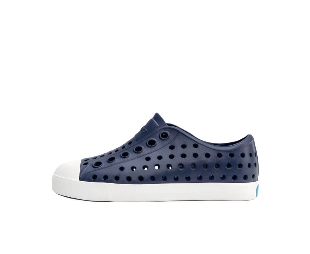 A navy blue sneaker with white sole, featuring a pattern of holes on the upper part.