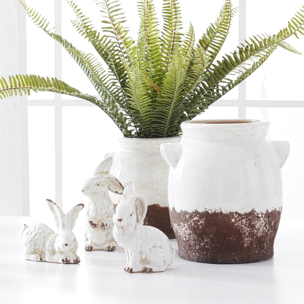 3 ceramic bunnies next to a plant
