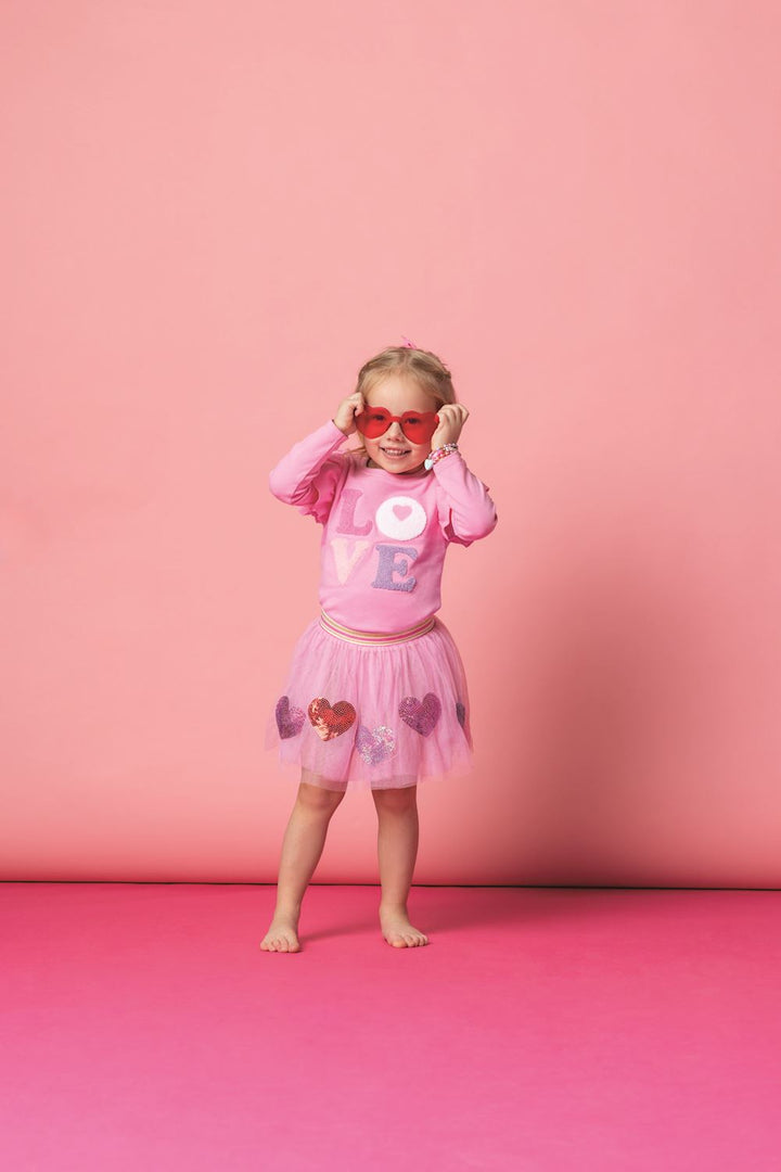 Young girl in pink outfit with heart designs on a pink background